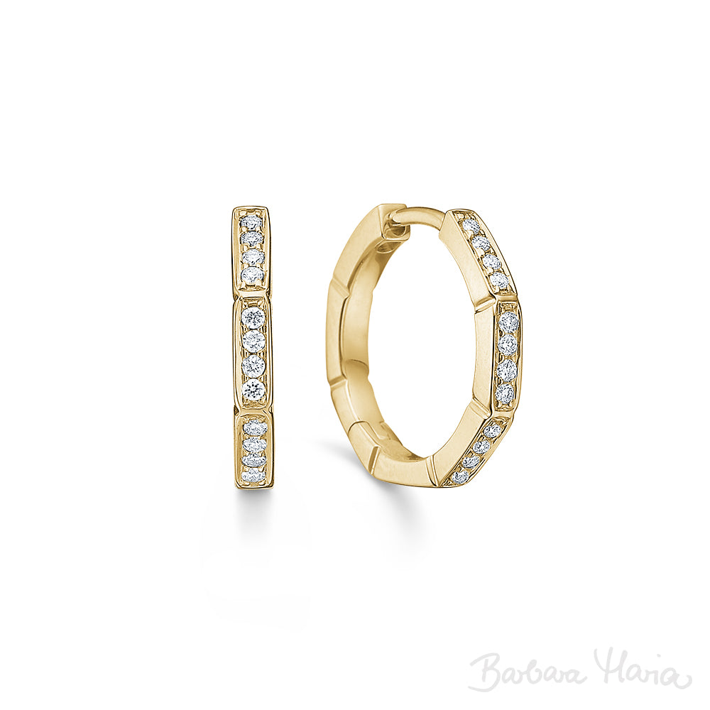 Devoted øreringene er fremstillet i 14 karat blankt guld med brillanter hele vejen rundt på øreringen, i alt 0,15 ct. TW/VS. Øreringene er designet af Maria Nielsen, Guldsmed Barbara Maria